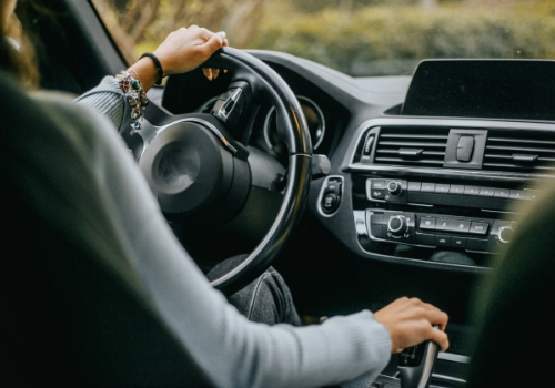 Woman driving a car seen from the inside.