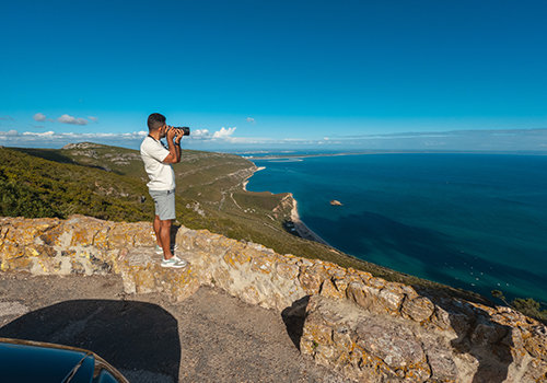 Turista a tirar fotografia num miradouro no Parque Natural da Arrábida