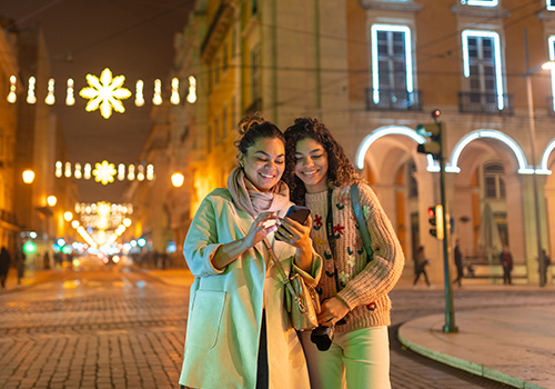 New Year’s Eve in Lisbon two young women looking at a mobile phone in the streets decorated with Christmas decorations in Lisbon.