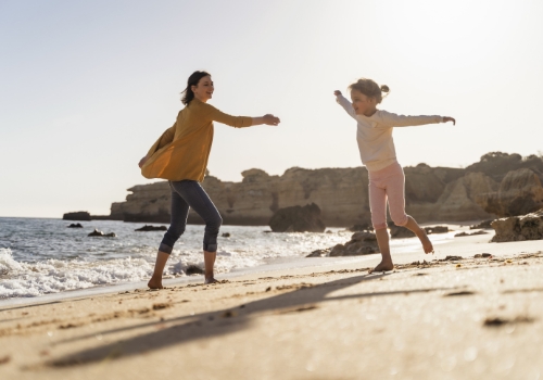 Mum and daughter playing on a beach in the Algarve in winter